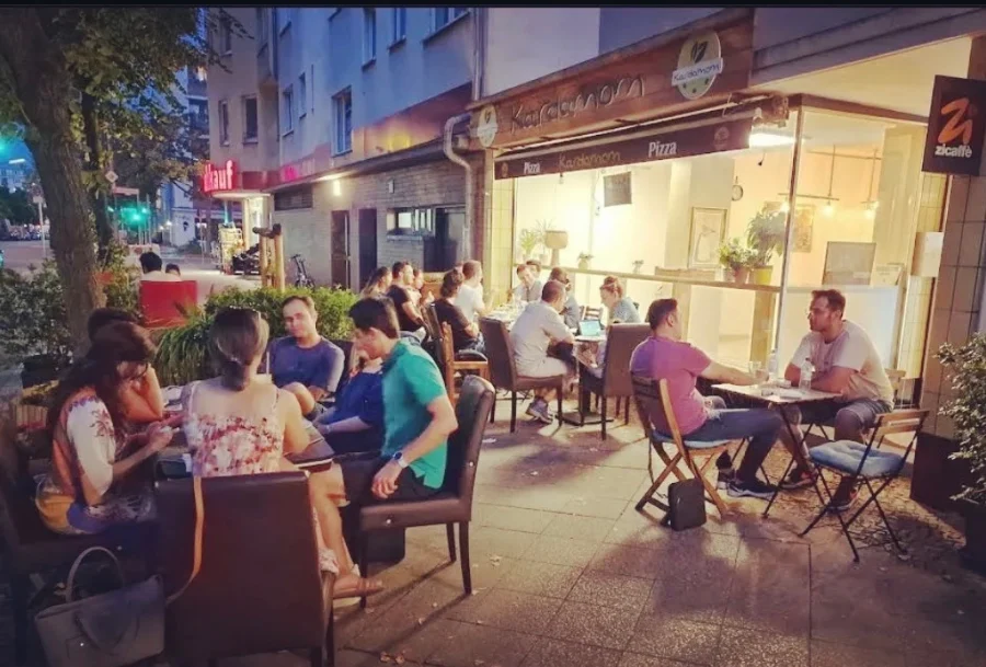 Mehrere Menschen sitzen an Tischen vor dem Café Kardamom.