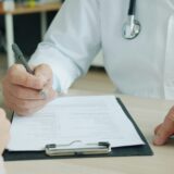 Arzt, der auf eine Patientenakte schreibt