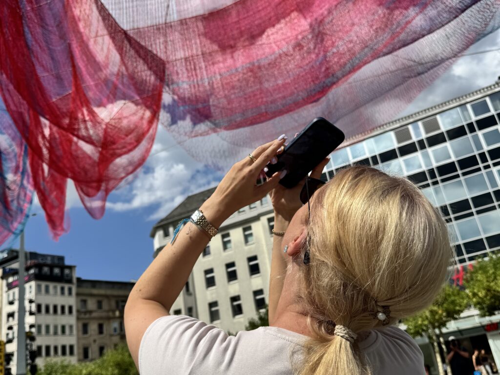 منحوتة «A Sky Full of Hope» المضيئة تحلّق فوق ساحة Konstablerwache في فرانكفورت. العمل للفنانة الأميركية جانيت إيكلمان، ويبلغ طوله أكثر من 25 متراً، وقد نُصّب ضمن فعاليات «World Design Capital 2026»- Bild: Viktoria Amalnews
