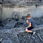 Дитина дивиться на зруйновану будівлю