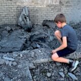 Ein Kind betrachtet ein zerstörtes Gebäude in Kyjiw.