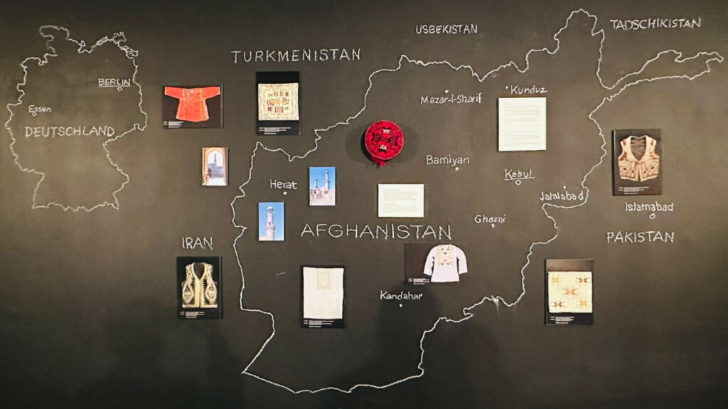 Das Bild zeigt zwei Karten, auf denen Städte eingezeichnet sind. Die linke Karte stellt Deutschland dar, die rechte Afghanistan. Darauf sind einzelne Bilder von Ausstellungsstücken verortet.