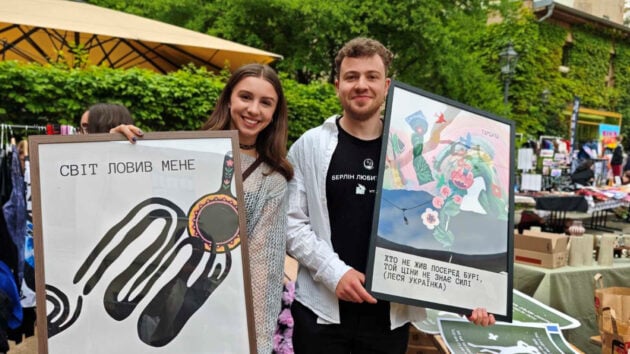 Anastasiia Molodii und Nazarii Pankevych halten Poster in die Kamera.